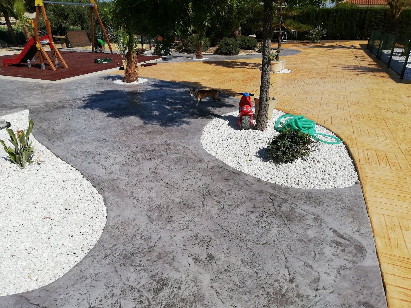 Una pasarela de hormigón en un parque con un área de juegos al fondo