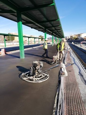 Un grupo de trabajadores de la construcción está trabajando en el andén de una estación de tren.