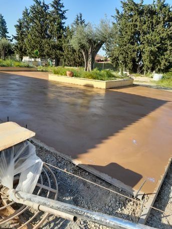 Se está construyendo un camino de entrada de hormigón con árboles al fondo.
