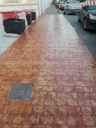 Una acera de ladrillos con coches aparcados a los lados.