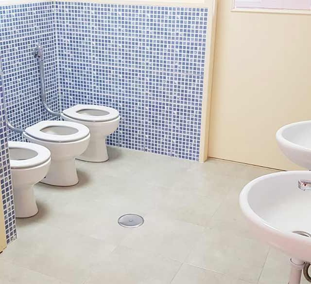 Un baño con tres inodoros y un lavabo.