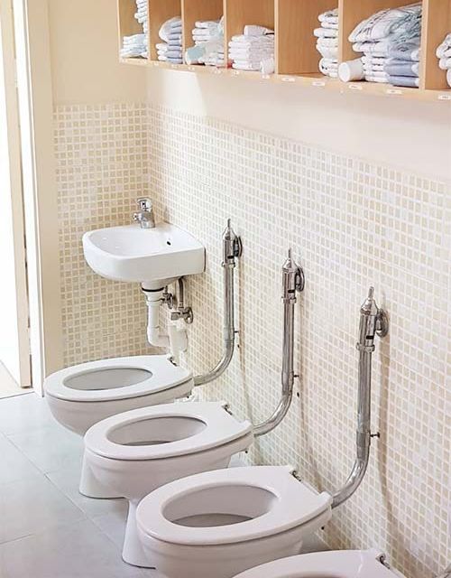 Una fila de inodoros y un lavabo en un baño.
