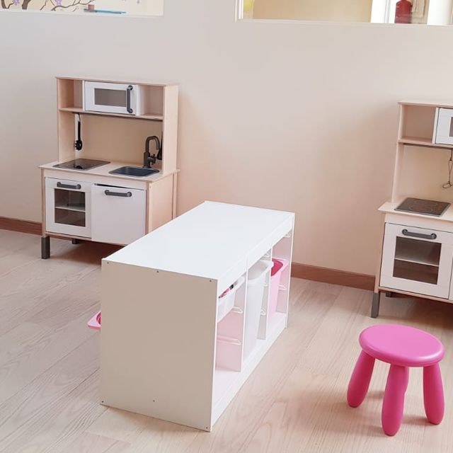 Un taburete rosa se encuentra frente a una cocina de juguete.