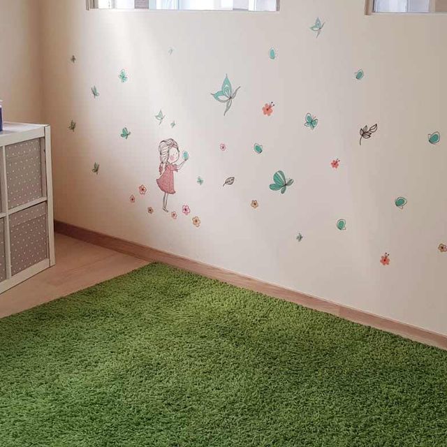 Una habitación con una alfombra verde y una pared con mariposas.