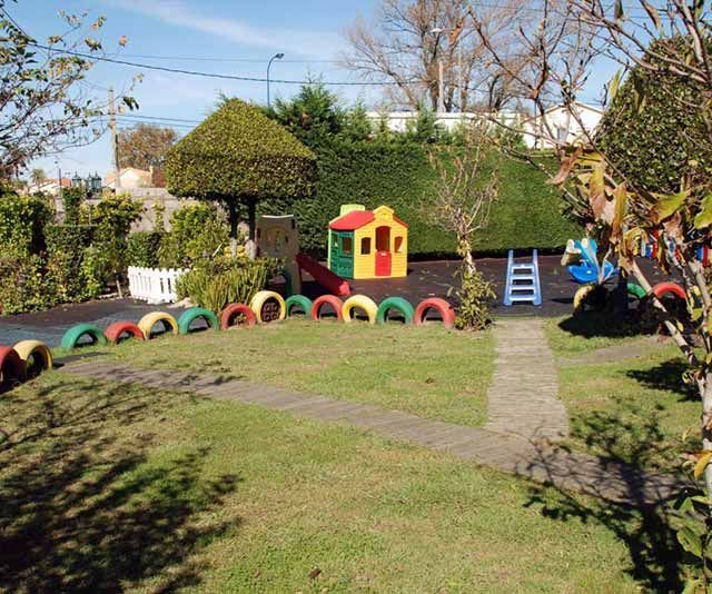 Un parque infantil con neumáticos y una casa.