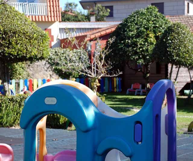 Un patio de recreo azul y morado con una casa al fondo.