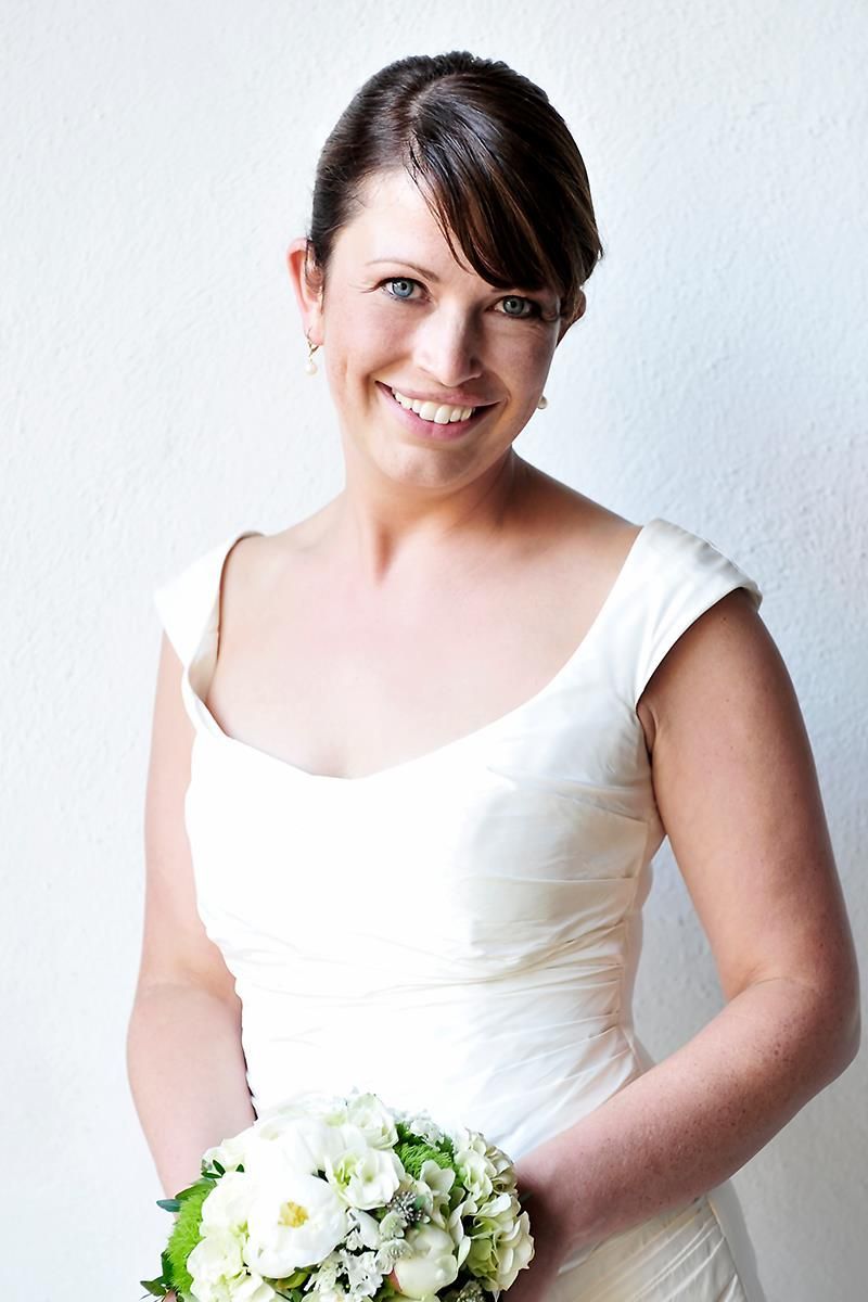 Eine Frau in einem weißen Kleid hält einen Strauß weißer Blumen