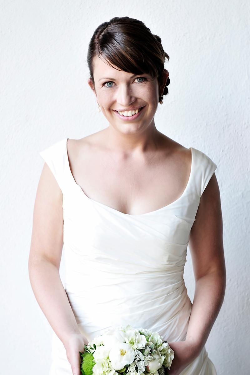 Eine Frau in einem weißen Kleid hält einen Strauß weißer Blumen