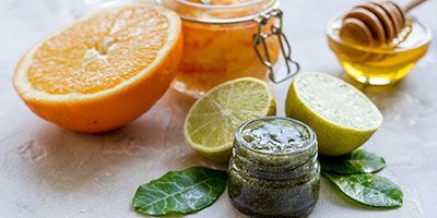 Ein Glas mit Honig, Zitronen, Orangen und Limetten auf einem Tisch.