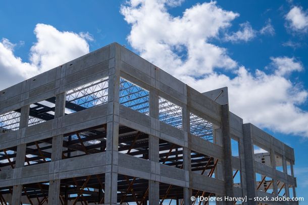 Ein großes im Bau befindliches Betongebäude mit einem blauen Himmel und Wolken im Hintergrund.