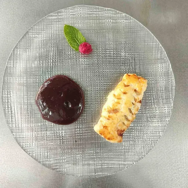 Un plato de comida con salsa de frambuesa y chocolate encima.