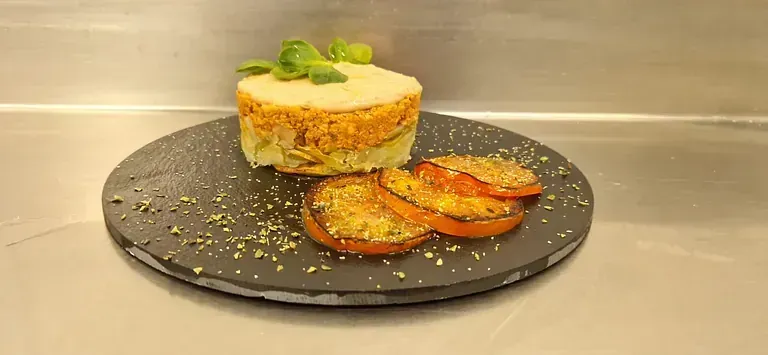 Un plato de comida con tomates y un pastel encima.