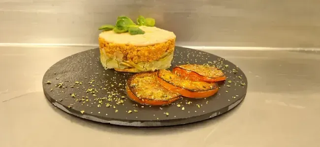 Un plato de comida con tomates y un pastel encima.