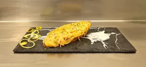 Un trozo de comida reposa en un plato negro sobre un mostrador.
