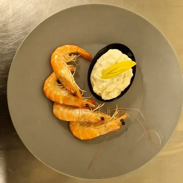 Un plato de camarones y un tazón de salsa sobre una mesa.