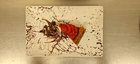Un plato blanco con una rebanada de pastel de fresa encima.
