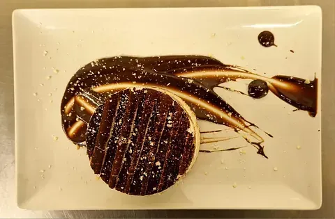Un plato blanco con un trozo de pastel de chocolate encima.