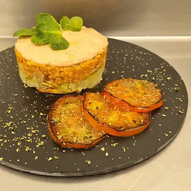 Un plato de comida con tomates y un pastel encima.