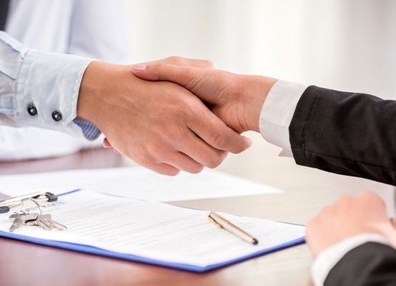 Manos temblando sobre un documento con llaves y un bolígrafo.