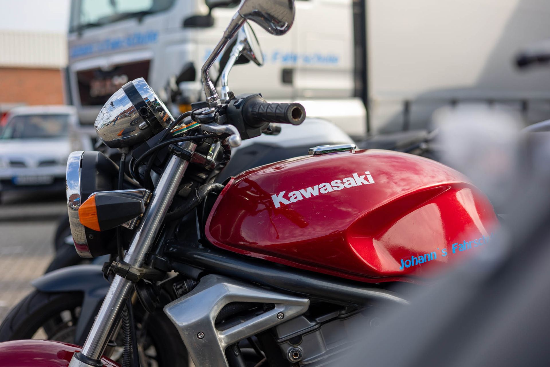 Ein rotes Kawasaki-Motorrad ist vor einem LKW geparkt.