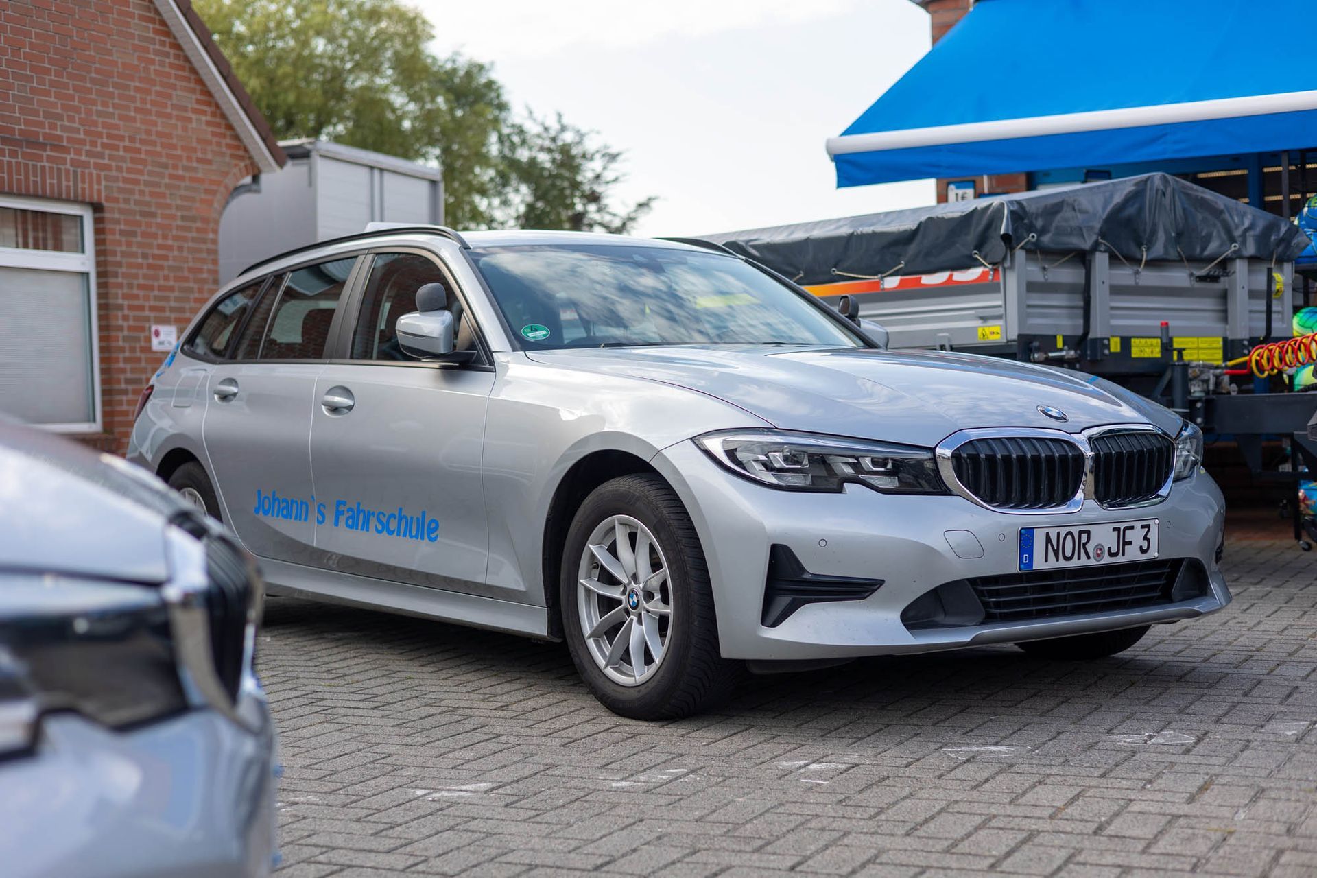 Ein silberner BMW 3er Kombi steht vor einem Backsteingebäude.