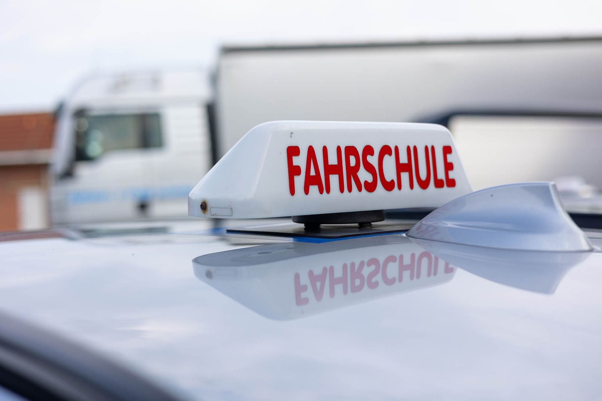 Ein Schild auf dem Dach eines Autos mit der Aufschrift „Fahrschule“.