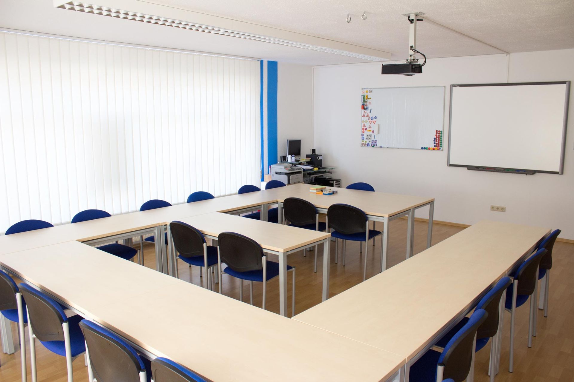 Ein Klassenzimmer mit Tischen und Stühlen und einer weißen Tafel