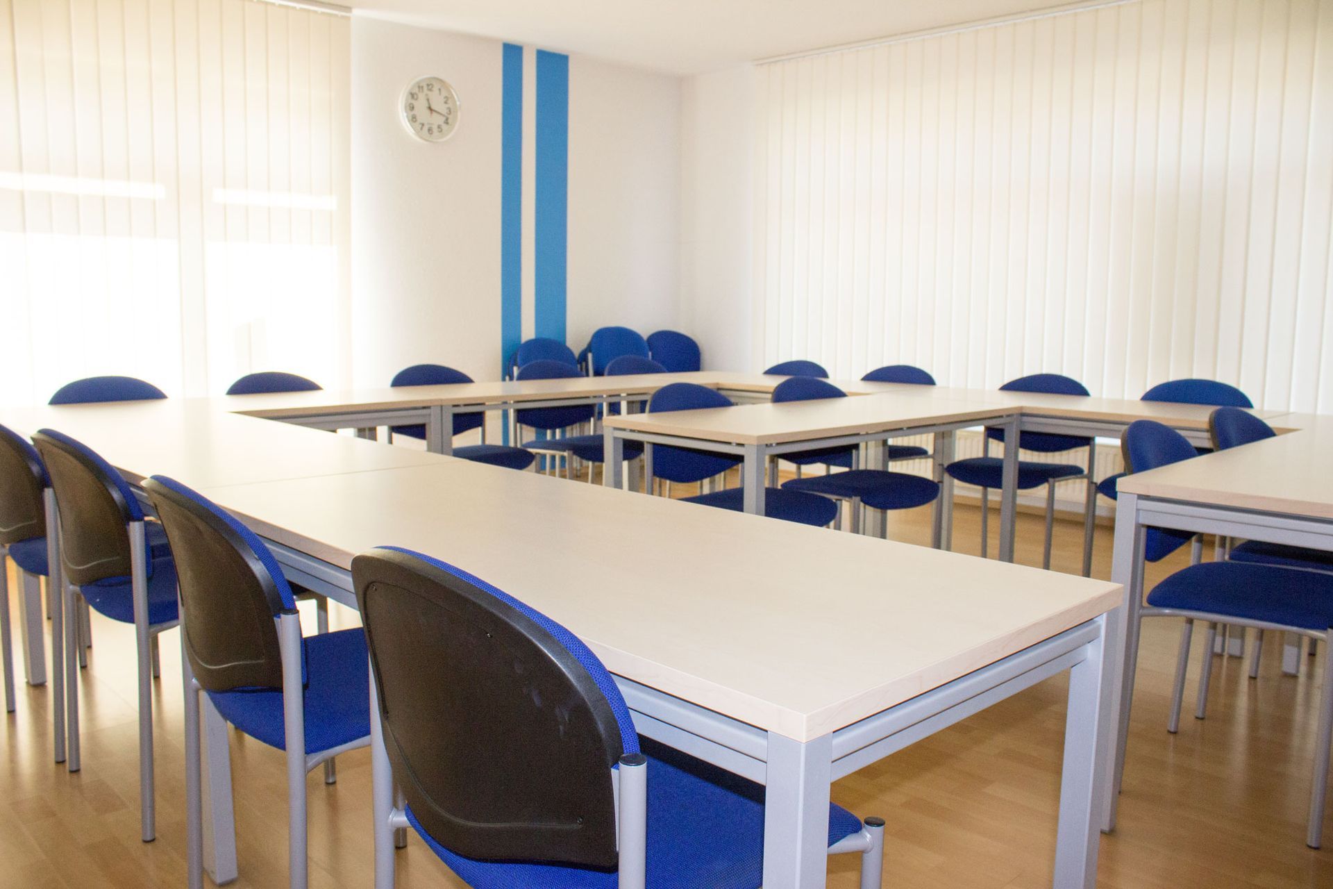 Ein Klassenzimmer mit Tischen und Stühlen und einer Uhr an der Wand