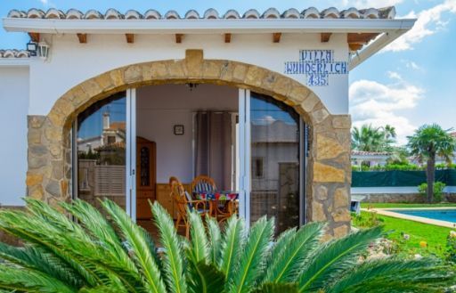 Una casa blanca con una puerta corrediza de vidrio y una palmera delante de ella.