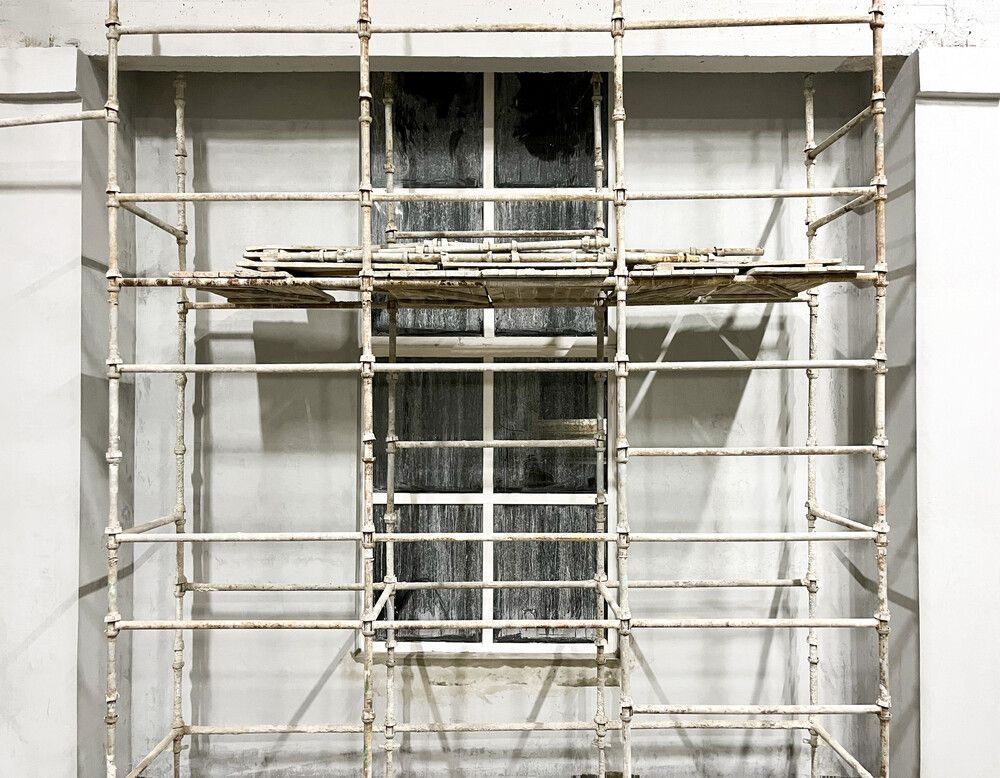 Se está construyendo una ventana en un edificio con andamios alrededor.
