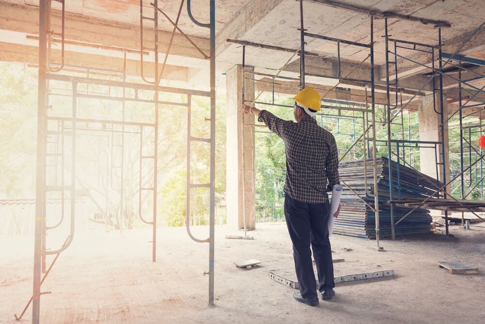 Un trabajador de la construcción está de pie en un edificio en construcción.