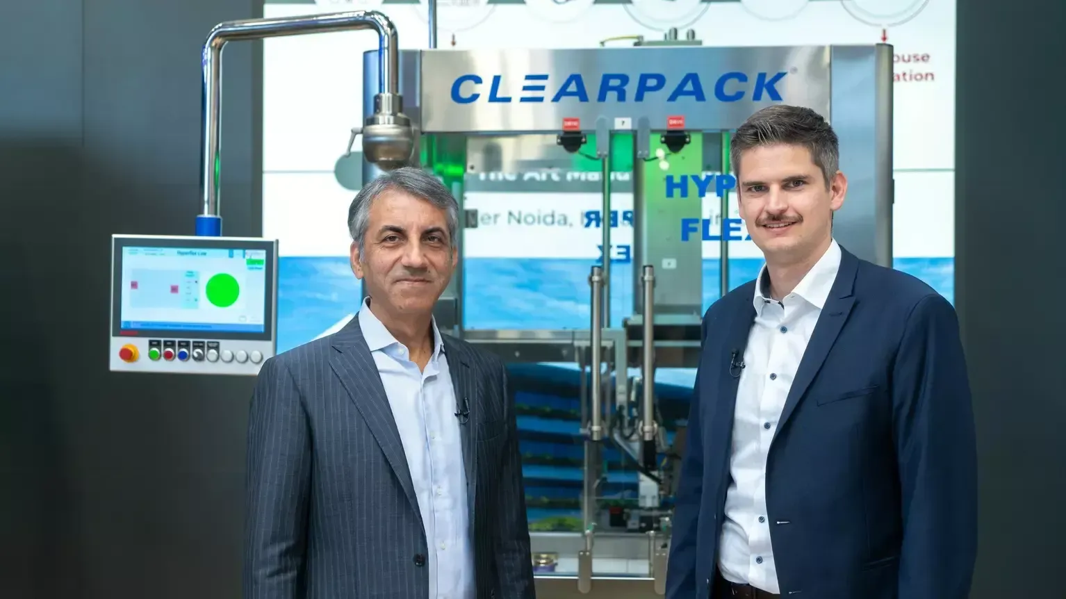 Twee mannen staan naast een CLEARPACK-machine in een fabrieksomgeving.