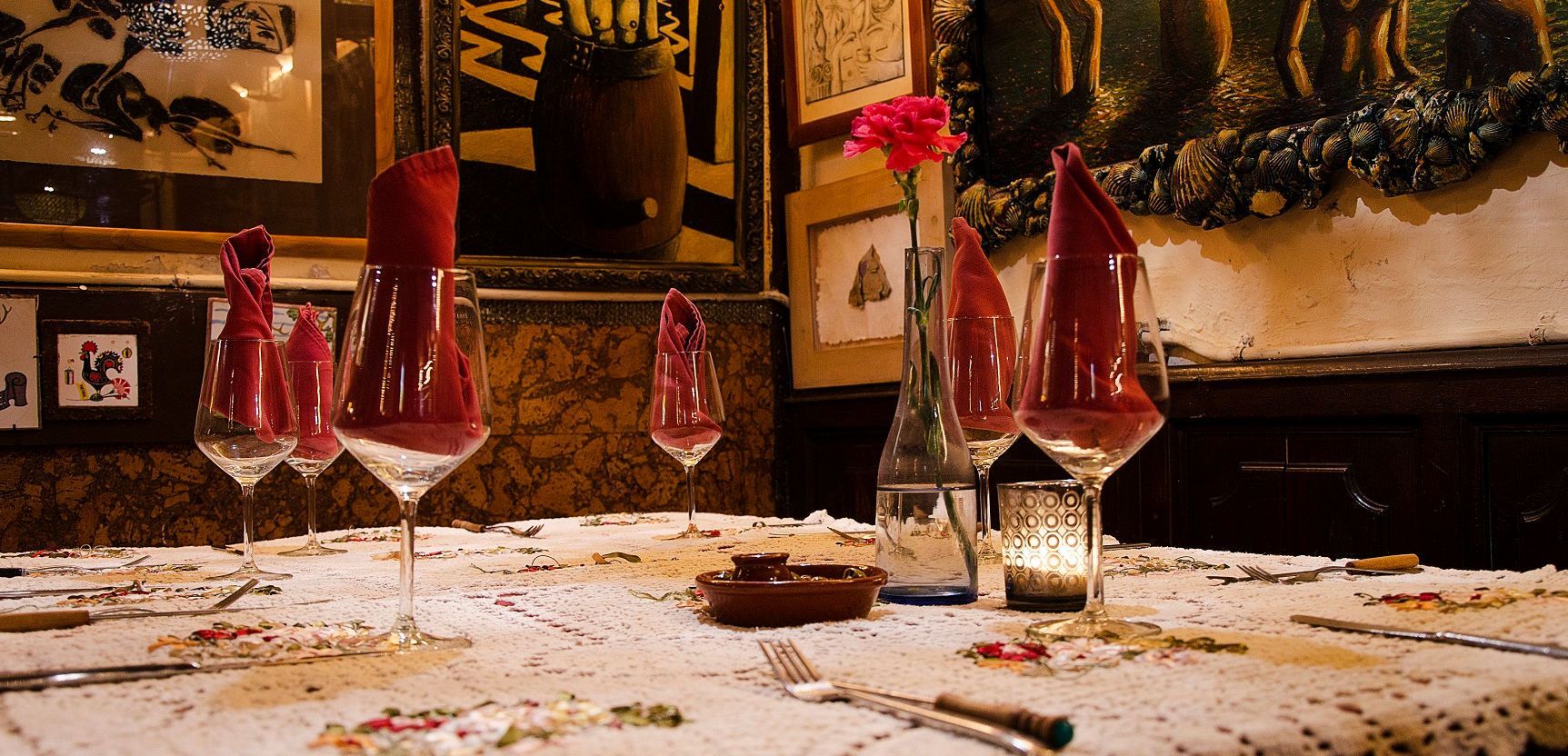 Una mesa con un jarrón de flores y copas de vino encima.
