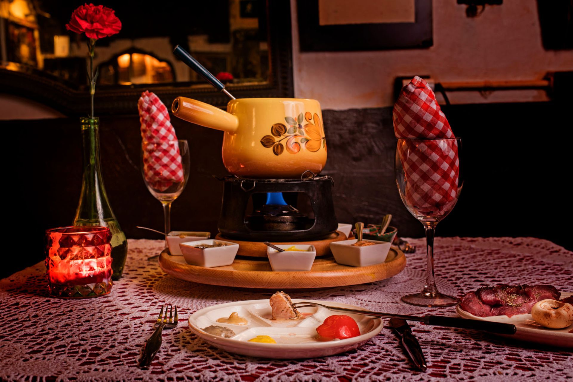 Una olla para fondue está sobre una mesa al lado de un plato de comida.