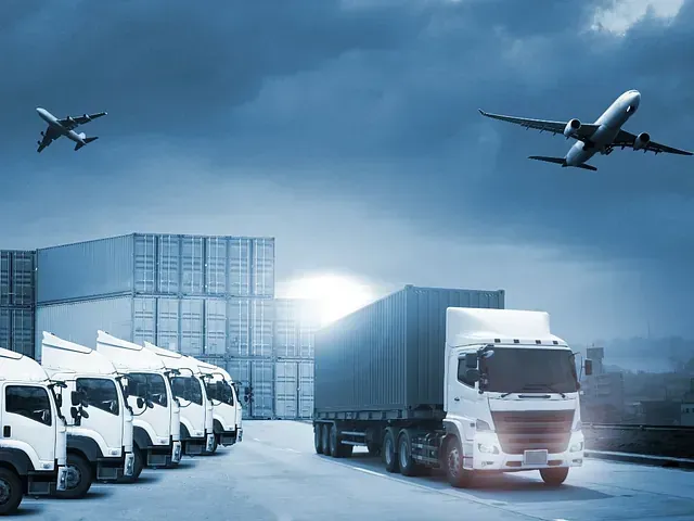 Una fila de camiones están estacionados en un estacionamiento con un avión volando sobre ellos.