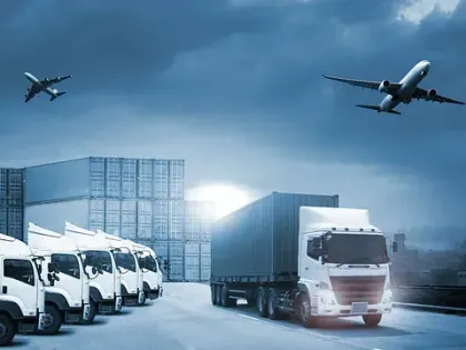 Una fila de camiones están estacionados en un estacionamiento con un avión volando sobre ellos.