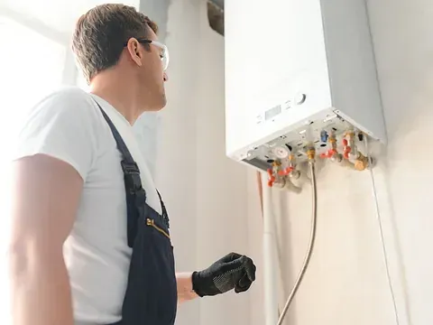 Un hombre está trabajando en una caldera en una habitación.