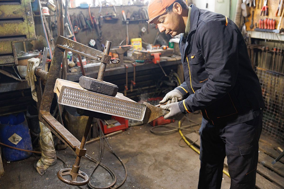Ouvrier dans son atelier qui réalise la construction d'un radiateur de voiture