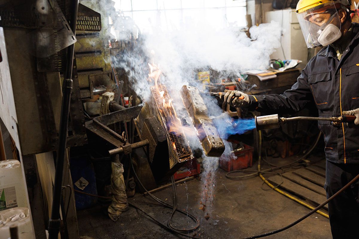 Ouvrier qui procède au nettoyage d'un radiateur automobile par décapage thermique