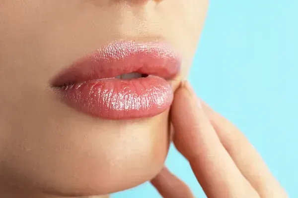 Un primer plano de los labios de una mujer con su mano en su cara.
