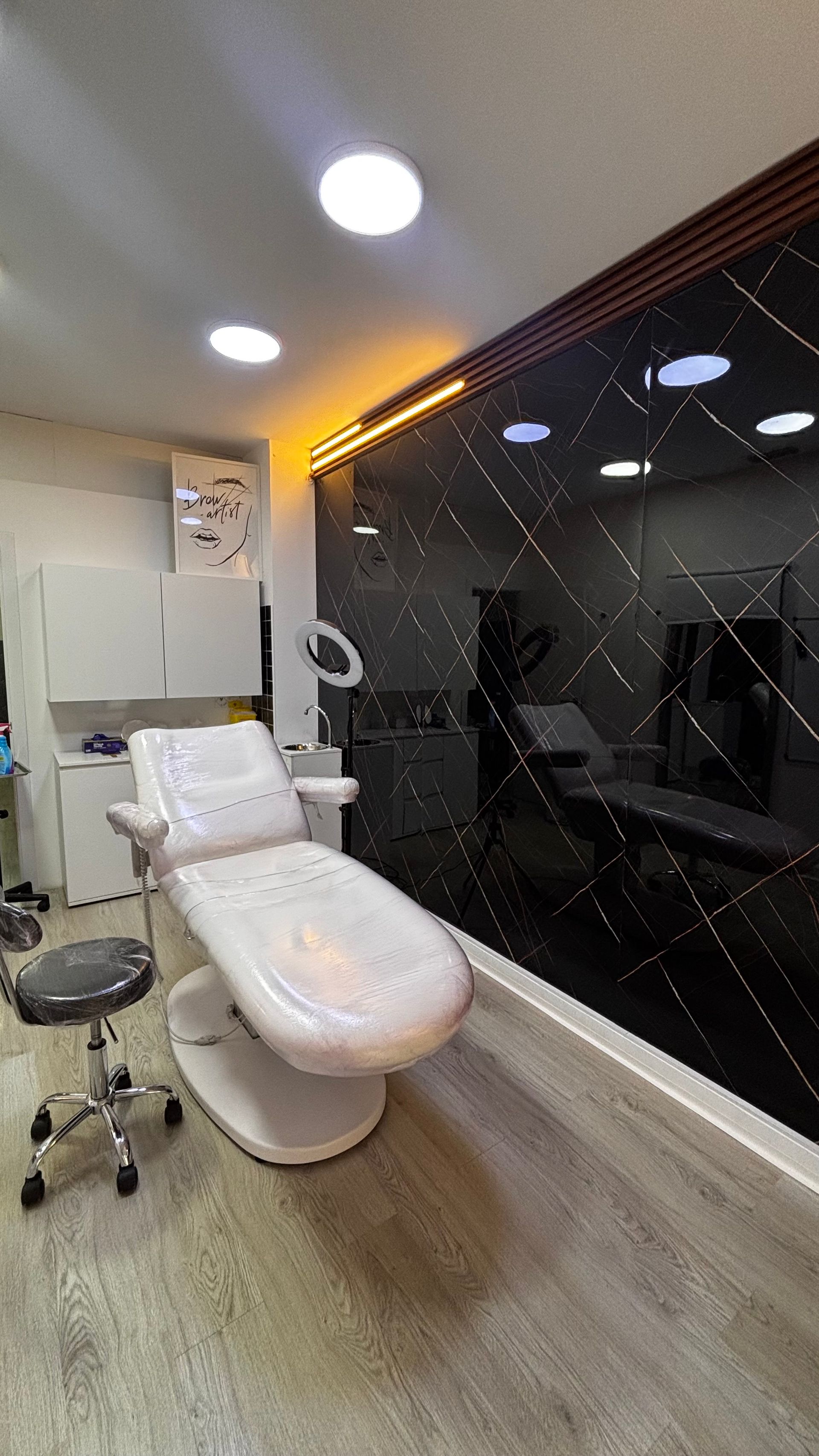 Sillón dental en una clínica moderna con pared acentuada en negro reflectante, iluminación brillante y gabinetes blancos.