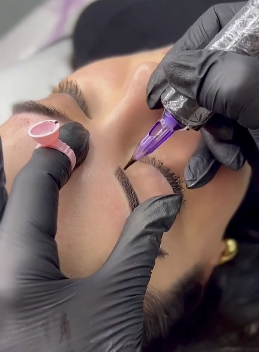 Un primer plano de una persona haciéndose un tatuaje en las cejas.