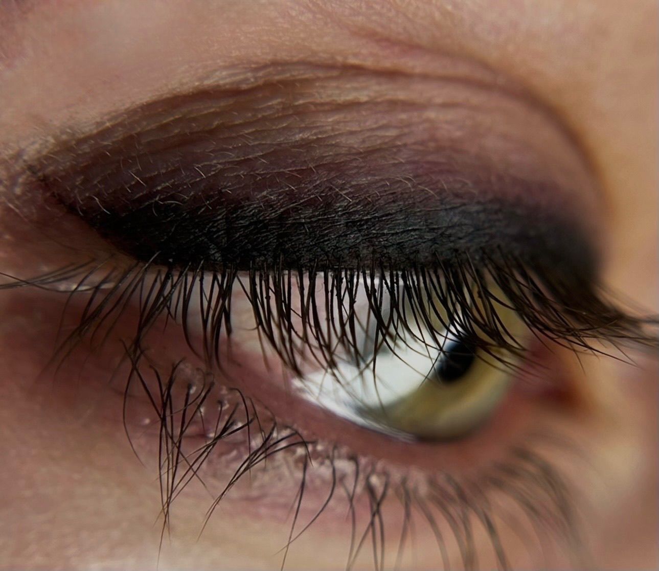 Primer plano de un ojo con sombra oscura y pestañas largas.