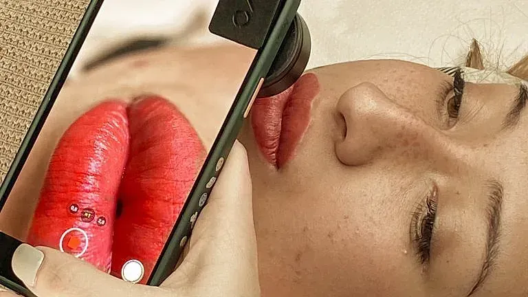 Una mujer se toma una foto de sus labios rojos con un teléfono celular.