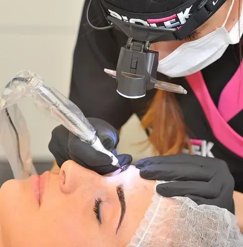 Una mujer que lleva una mascarilla y guantes se está haciendo un tatuaje en el ojo.
