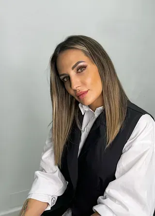 Una mujer lleva un chaleco negro y una camisa blanca.