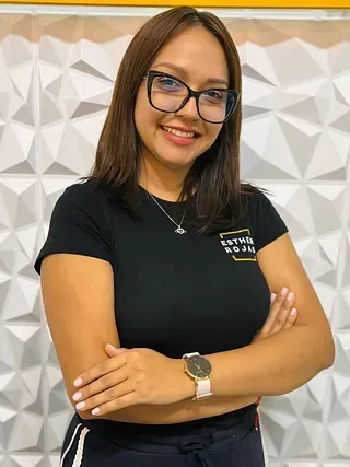 Una mujer que lleva gafas y una camisa negra está de pie con los brazos cruzados.
