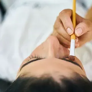 Una mujer se está pintando las cejas con un pincel.