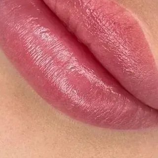 Un primer plano de los labios de una mujer con lápiz labial rosa.