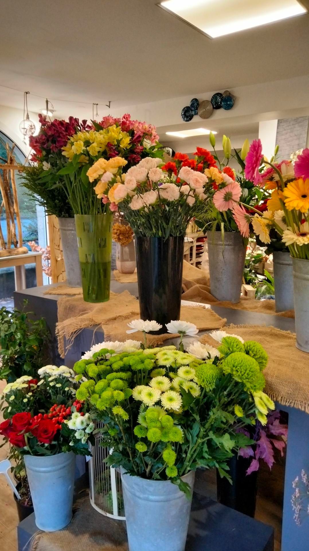 Des bouquets de fleurs éclatants, présentés dans des vases variés, ornent les tables d'une boutique de fleurs lumineuse.